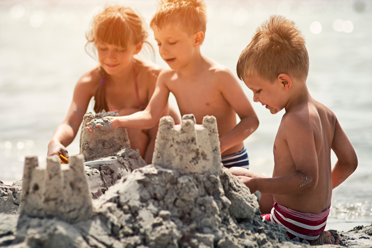 group of children on beach building a sandcastle